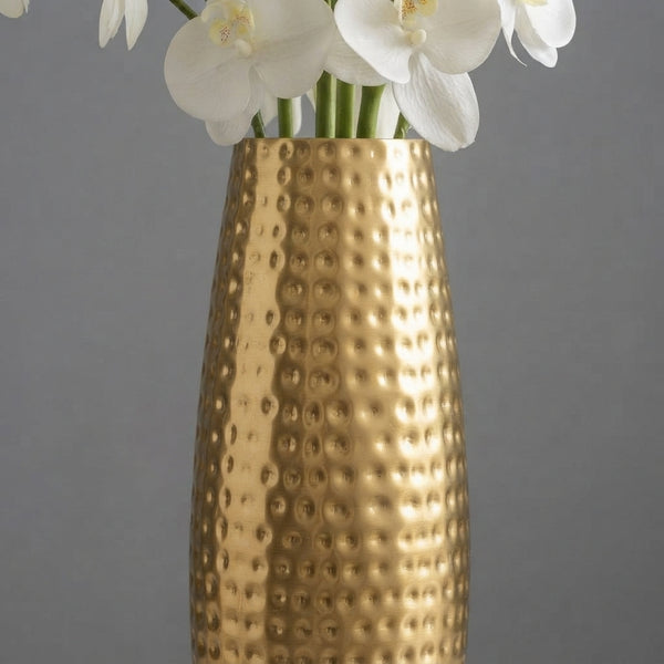 Close-up of a hammered metal vase showing intentional surface indentations reflecting light against a neutral background.